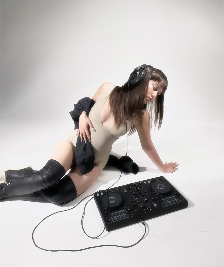 Event promotion content — model with headphones beside a DJ controller in a white studio, event campaign photography by Maison Division